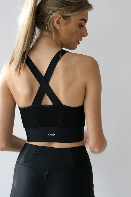 Vrouw draagt zwarte nauwsluitende sport crop top van JUSS7 Sportswear