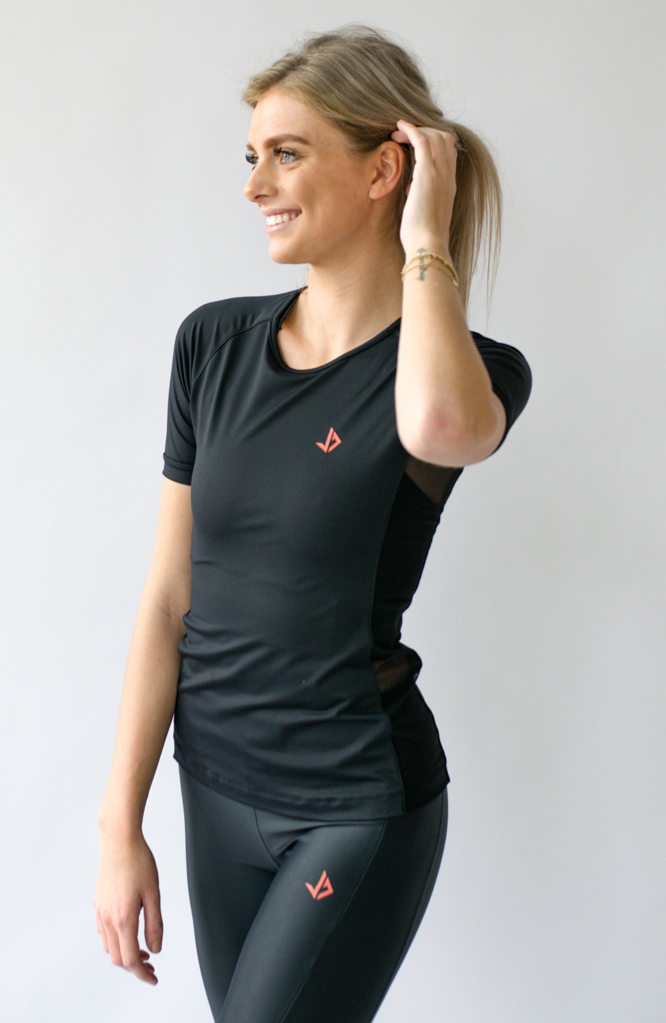 Lange vrouw draagt zwart sportshirt met korte mouwen van JUSS7 Sportswear